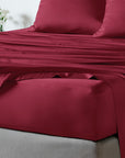 bambaw cozy bamboo bed sheets close up on a bed with fitted sheets and pillows in burgundy red colour