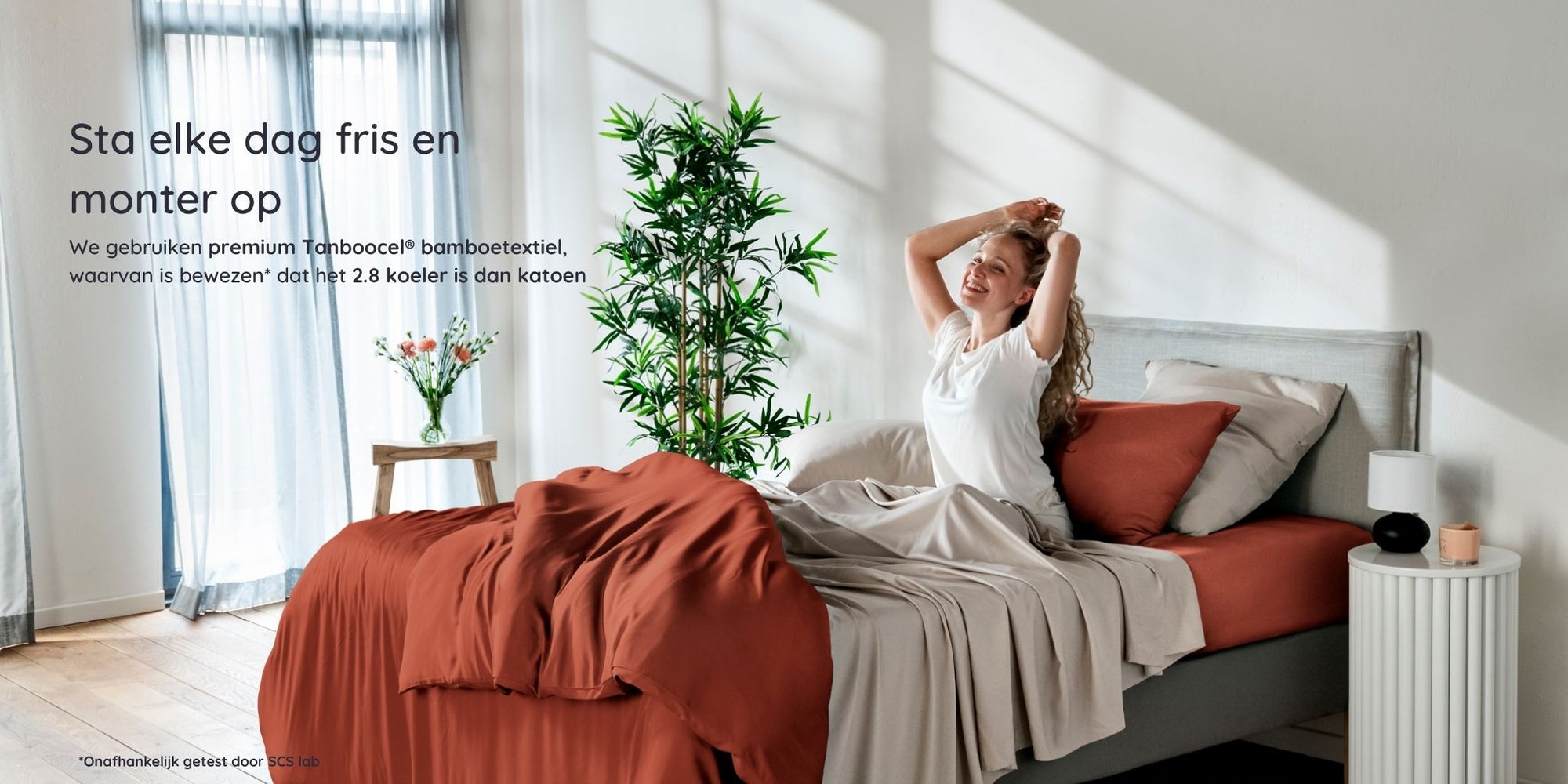 Woman waking up in a bright bedroom in a bed with bambaw cozy bamboo bedsheets in terraccota and sand colours with natural light and plants.